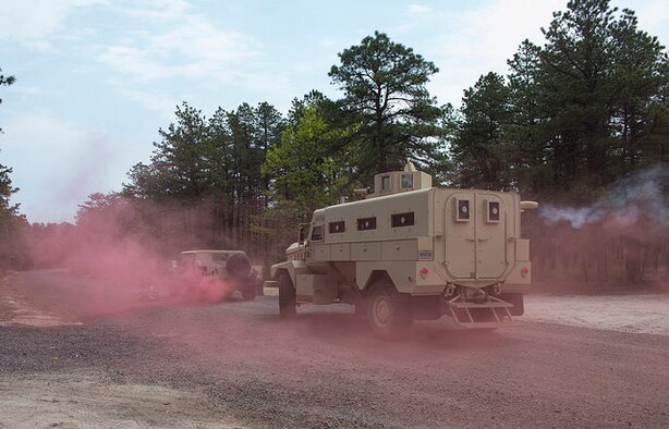 Red smoke surrounds military vehicles simulating an improvised explosive device explosion during a field training exercise on Joint Base McGuire-Dix-Lakehurst, N.J. May 6, 2015. The EOD team replicated situations from Iraq and Afghanistan to take advantage of lessons learned there. (U.S. Air Force photo by Airman 1st Class Joshua King)