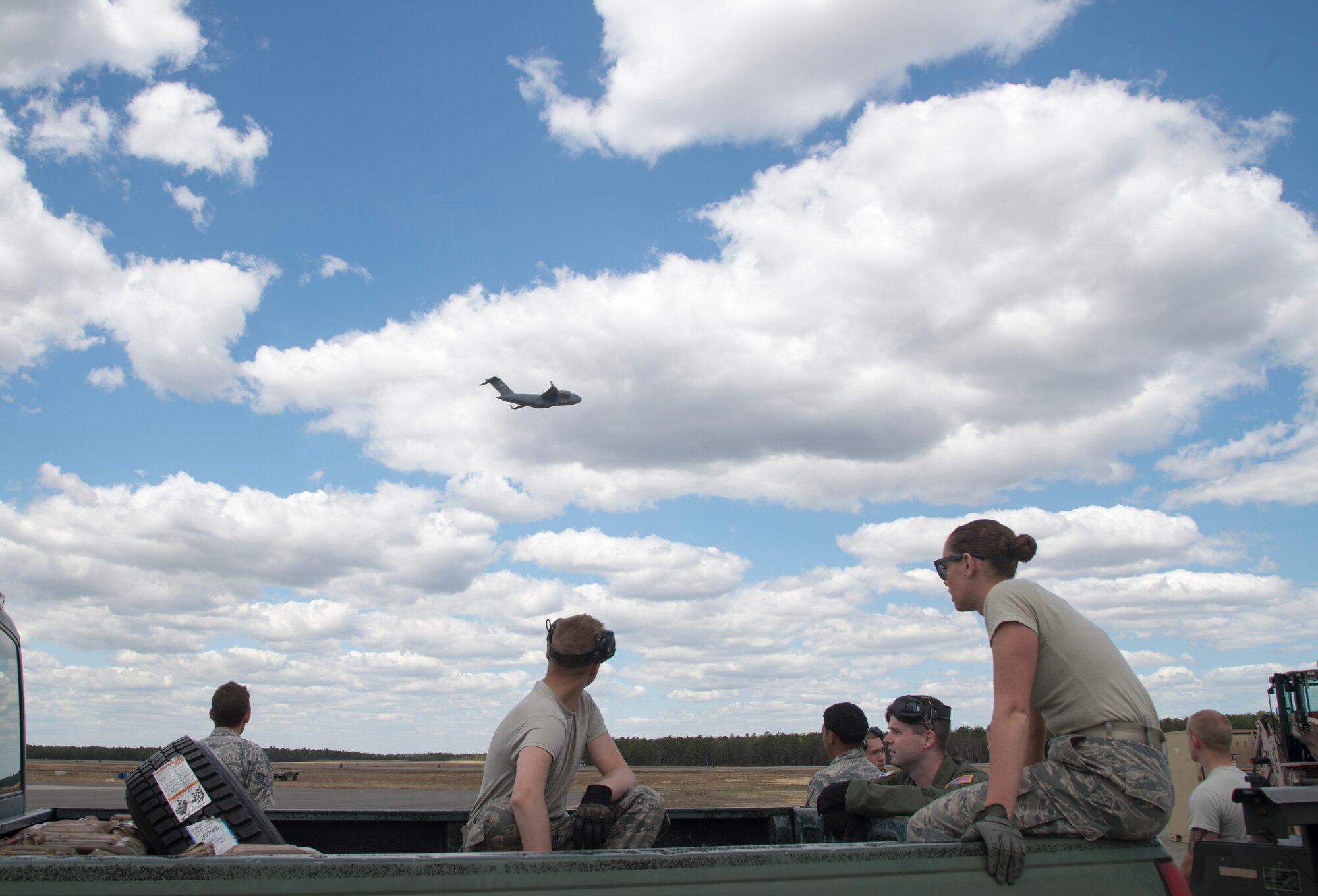 Airmen from the 621st Contingency Response Wing watch a U.S. Air Force Globemaster III C-17 fly during an exercise at Joint Base McGuire-Dix-Lakehurst, N.J., April 29. The exercise helped train the crew members from five C-17’s, conducted engine running offloads, communication proficiency training, night vision goggle training, and a ramp coordinator chief received upgraded training during this exercise. (U.S. Air Force photo/Staff Sgt. Gustavo Gonzalez)