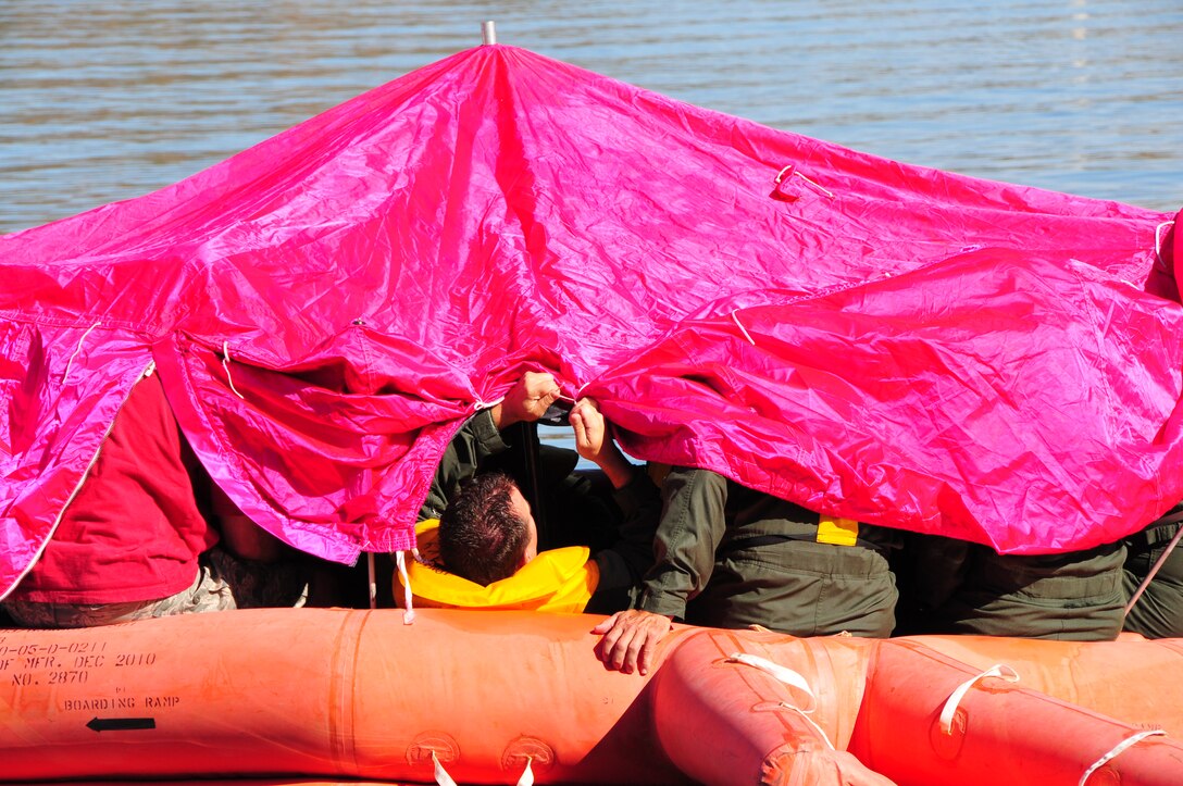 Tech. Sgt. Jason Snodgrass, 161st Air Refueling Wing boom operator, ties the side of the 20 man life raft canopy up for ventilation during water survival training at Lake Pleasant, Peoria, Ariz., May 3, 2015. Water survival training encompasses equipment familiarization and processes in the event of an emergency over-water ditching scenario.    (U.S. Air National Guard photo by Master Sgt. Kelly M. Deitloff)