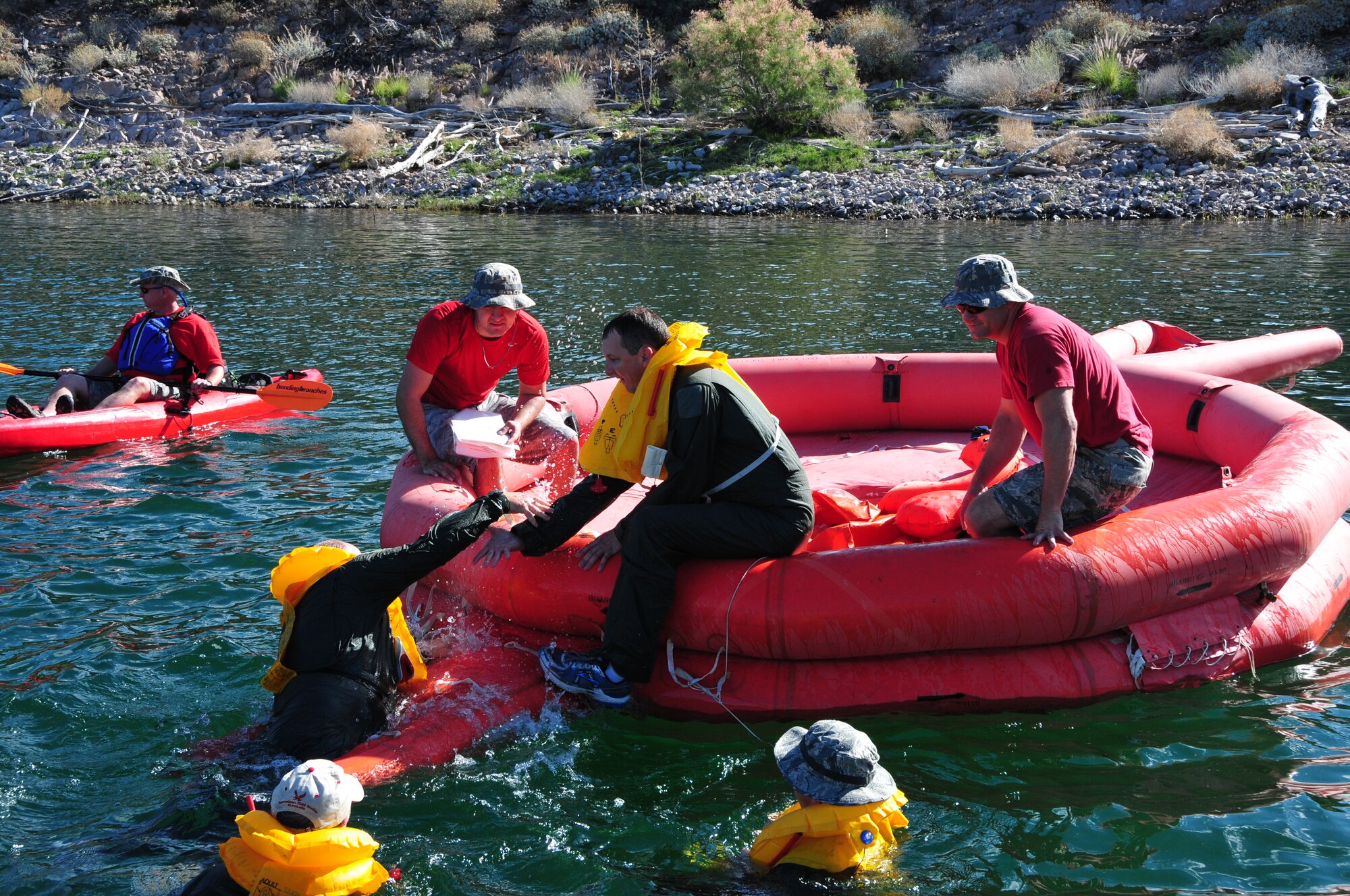 Senior Airman Michael Hastings, 161st  Air Refueling Wing boom operator, assists Col. Chris Triebel, 161st Air Refueling Wing vice commander, onto a 20 man life raft during water survival training May 3, 2015, at Lake Pleasant, Peoria, Ariz. Water survival training encompasses equipment familiarization and processes in the event of an emergency over-water ditching scenario.    (U.S. Air National Guard photo by Master Sgt. Kelly M. Deitloff)
