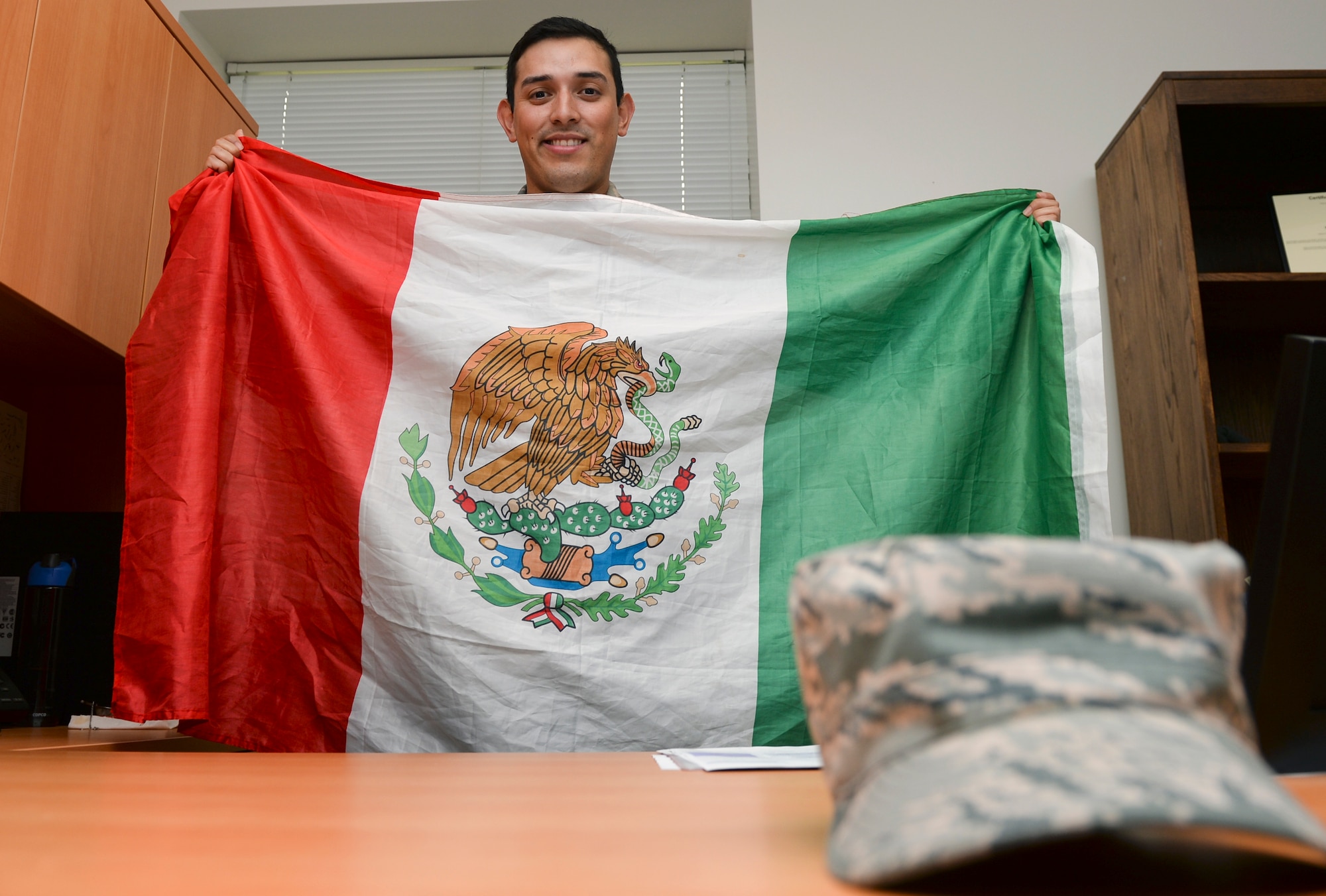 Senior Airman Christian Luevano, 22nd Contracting Squadron contract administrator, poses with a Mexican flag May 8, 2015, at McConnell Air Force Base, Kan. Luevano is a Tijuana native who moved to San Diego when he was 15 years old and joined the Air Force in July 2012. (U.S. Air Force photo by Senior Airman Colby L. Hardin)
