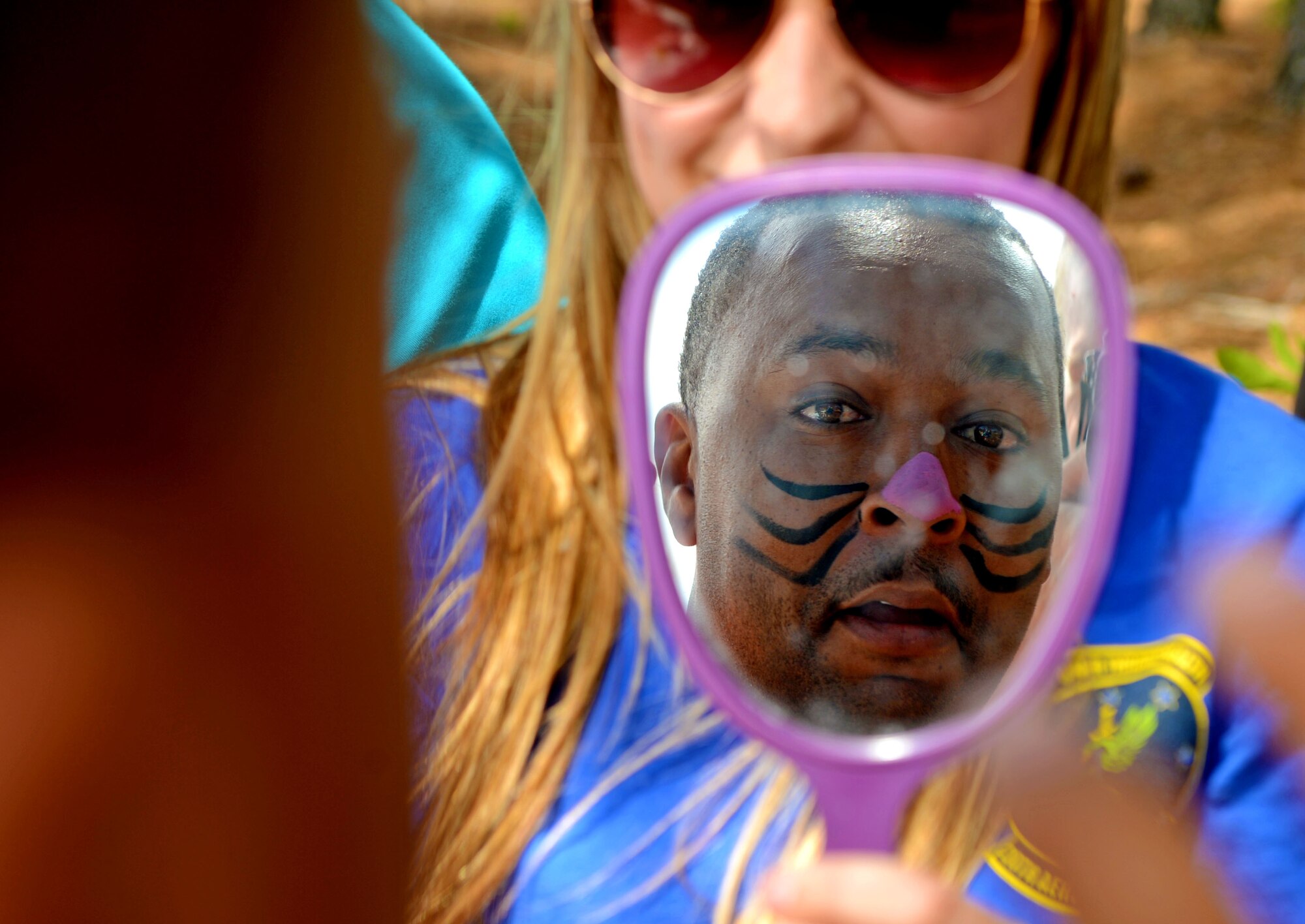U.S. Air Force Tech. Sgt. Clyde Rankins, 20th Logistics Readiness Squadron quality assurance inspector, looks at his face paint in a mirror during a “Big-A” game day at Shaw Air force Base, S.C., May 8, 2015. Face painting, bouncy castles, corn-hole and food were provided for Airmen and their families. (U.S. Air Force photo by Senior Airman Jensen Stidham/Released)