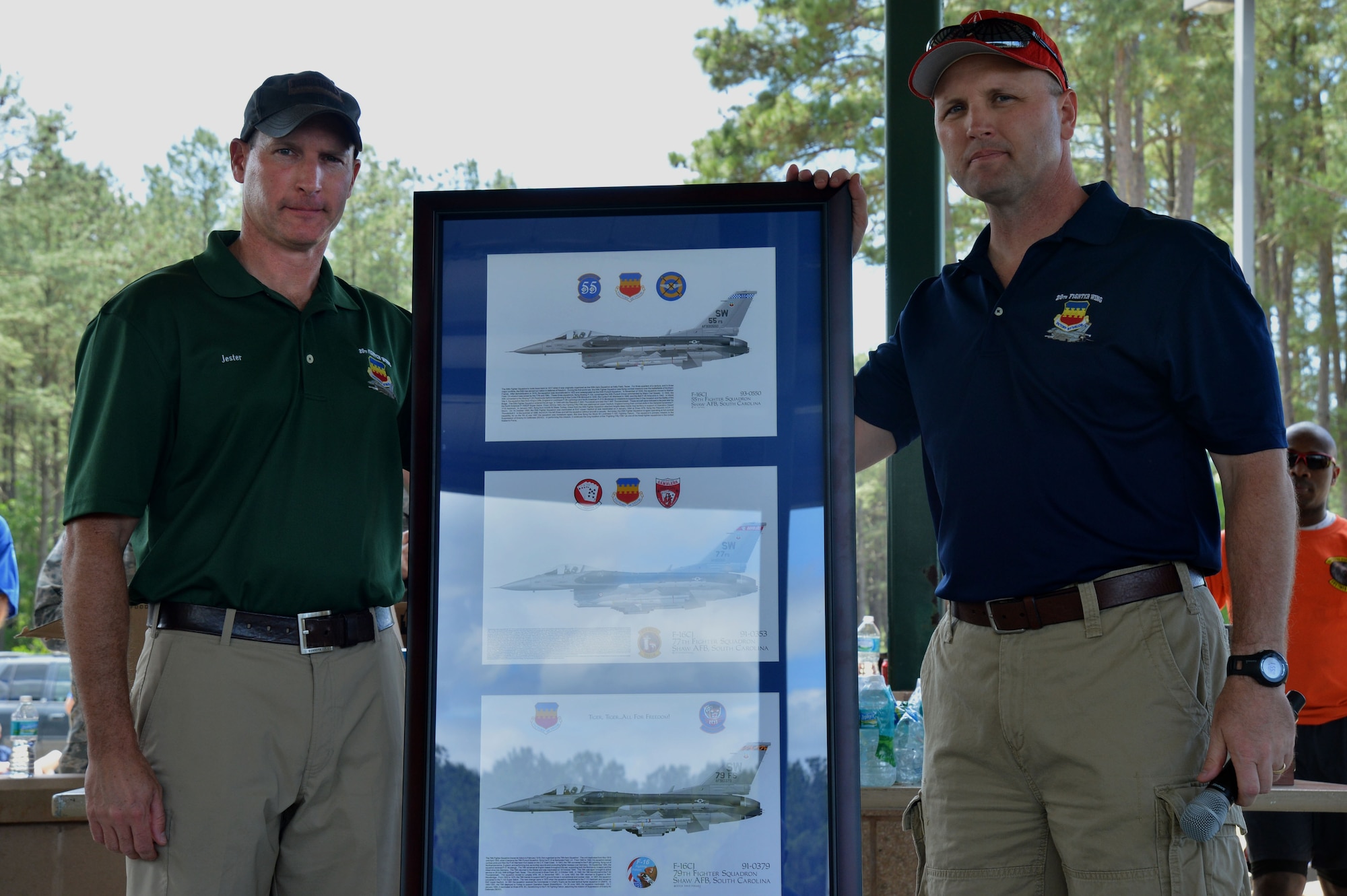 U.S. Air Force Col. Stephen Jost, 20th Fighter Wing commander, presents Chief Master Sgt. Charles Mills, 20th FW command chief, with a going away present during the Big “A” Game Day challenge at Shaw Air Force Base, S.C., May 8, 2015. The challenge was held to gather Airmen assigned to the 20th FW to say “good-bye” to Mills. (U.S. Air Force photo by Airman 1st Class Michael Cossaboom/Released)