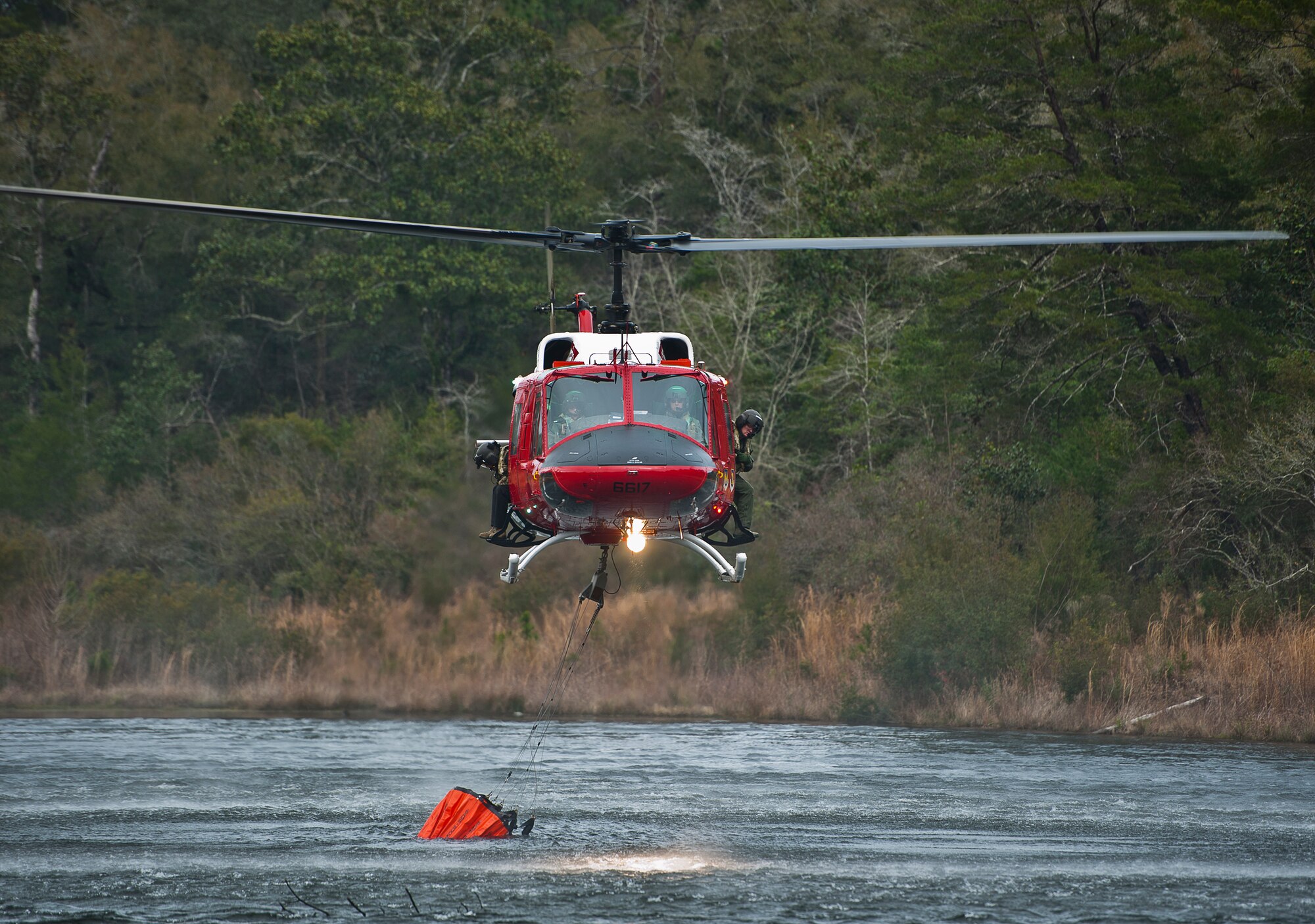 A 413th Flight Test Squadron UH-1 Huey gathers up a bucket of water from Anderson Pond during a training mission at Eglin Air Force Base, Fla.  The water bucket operations training is required for flight crews to maintain their firefighting proficiencies.  The 413th helicopters can be tasked by the 96th Test Wing to support Jackson Guard with fire management.  They supported a firefighting effort during a range fire North of Hurlburt Field in May 2012. (U.S. Air Force photo/Samuel King Jr.)