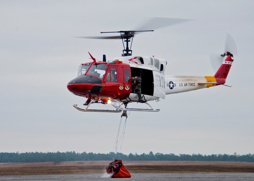 A 413th Flight Test Squadron UH-1 Huey pours out a bucket of water during a training mission at Eglin Air Force Base, Fla.  The water bucket operations training is required for flight crews to maintain their firefighting proficiencies.  The 413th helicopters can be tasked by the 96th Test Wing to support Jackson Guard with fire management.  They supported a firefighting effort during a range fire North of Hurlburt Field in May 2012. (U.S. Air Force photo/Samuel King Jr.)