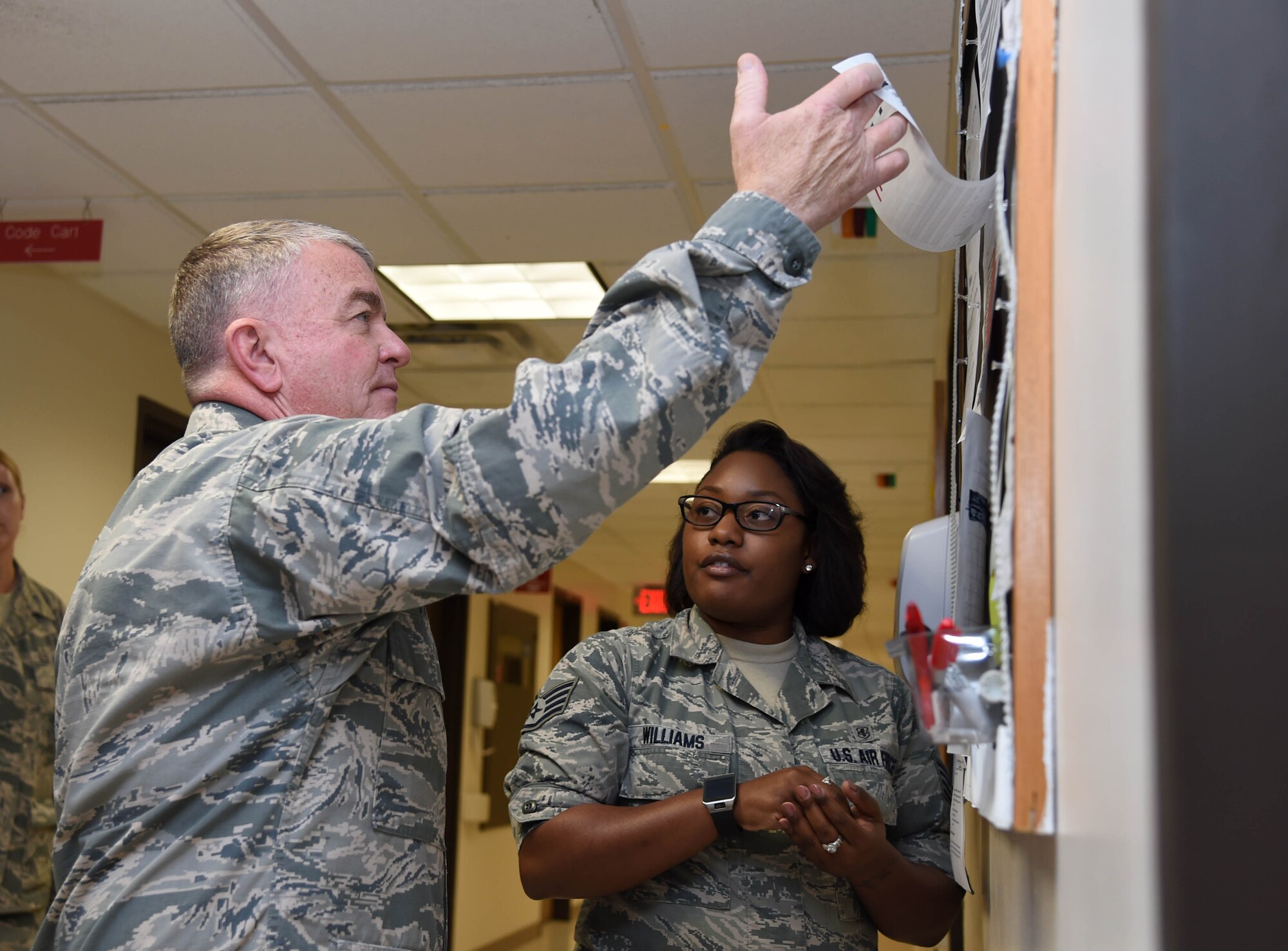 Staff Sgt. Dominique Williams, 59th Medical Support Squadron cardiopulmonary technician, explains her unit’s Lean Daily Management initiatives to Air Force Surgeon General Lt. Gen. (Dr.) Thomas Travis during his visit May 7, 2015 at the Wilford Hall Ambulatory Surgical Center, Joint Base San Antonio-Lackland, Texas. During his visit, Travis viewed Lean Daily Management boards, a process improvement tool used throughout the medical wing. (U.S. Air Force photo/Staff Sgt. Jerilyn Quintanilla)