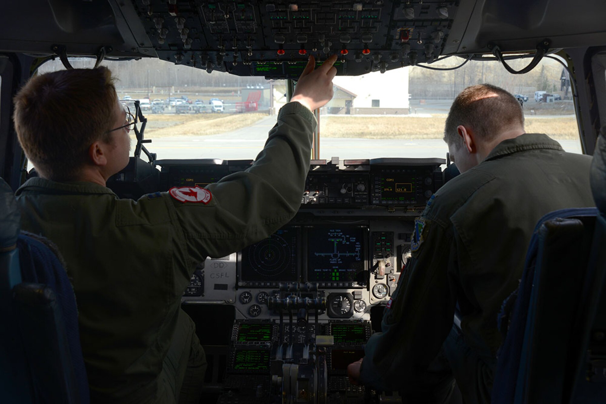Capt. Matthew Lawton, 517th Airlift Squadron deputy readiness flight commander, and Capt. Brandon Ongna, 517th AS deputy standardization and evaluation flight commander, both C-17 Globemaster III pilots, run through a preflight checklist before departing on a humanitarian mission to Nepal May 1. (U.S. Air Force photo/Airman Christopher Morales)