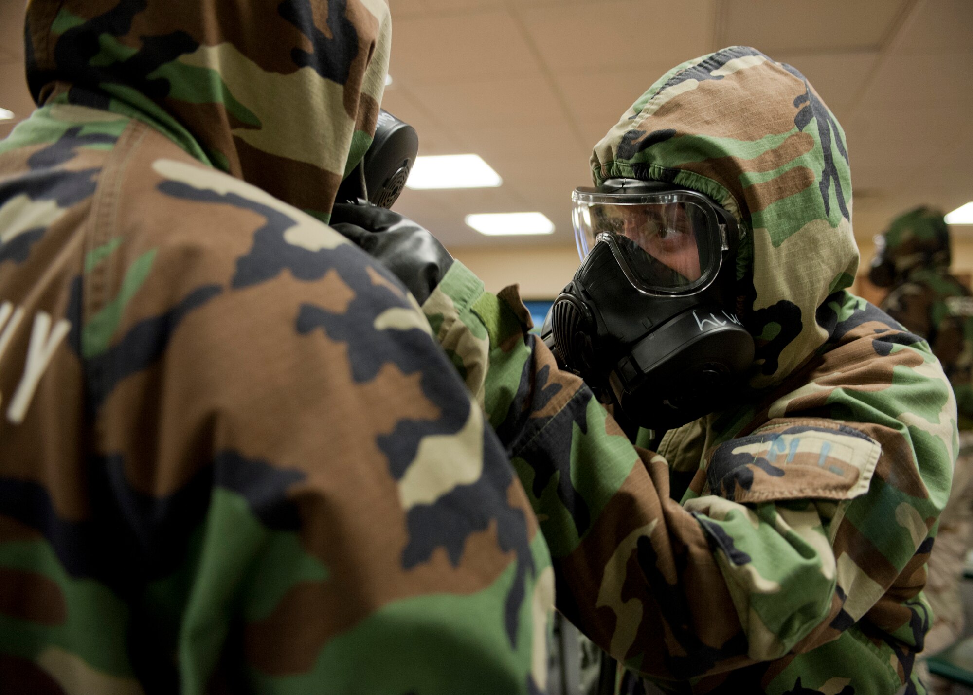 Tech. Sgt. Danielle Frazier, 414th Combat Training Squadron red flag liaison, checks a wingman’s protective equipment to ensure a proper seal during a chemical, biological, radiological and nuclear defense survival skills training course at Nellis Air Force Base, Nev., April 30, 2015. Buddy checks are designed to ensure Airmen have properly assembled their mission-oriented protective posture gear. (U.S. Air Force photo by Airman 1st Class Jake Carter)