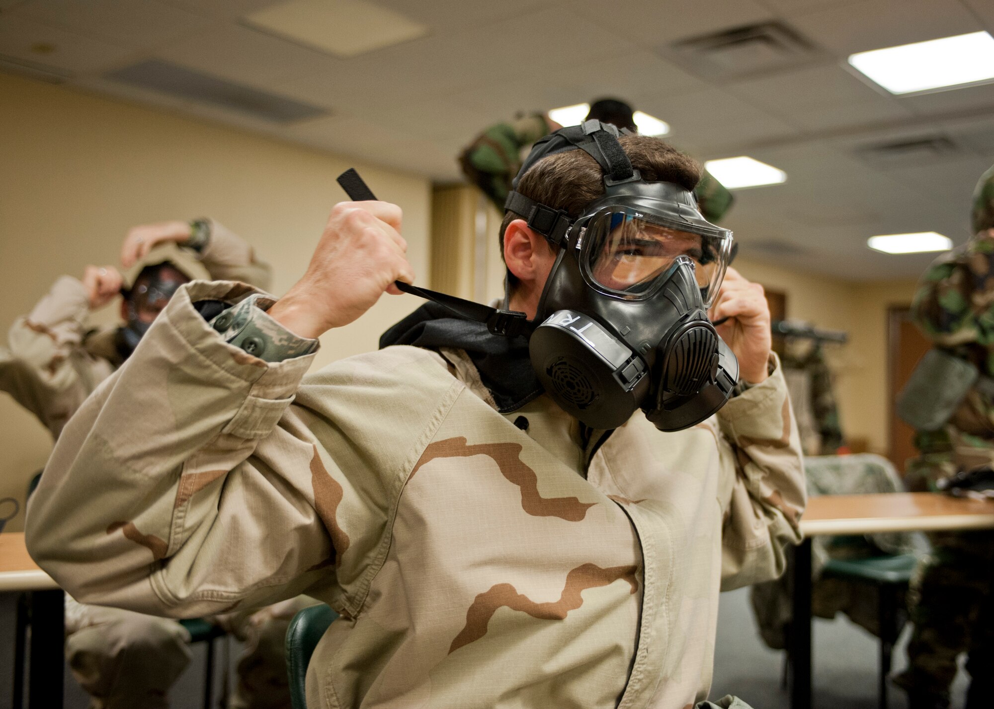 Senior Airman Jerod Hopkins, 99th Comptroller Squadron, pulls his straps tight on his gas mask to ensure a proper seal during a chemical, biological, radiological and nuclear defense survival skills training course at Nellis Air Force Base, Nev., April 30, 2015. CBRN training is intended to prepare Airmen for the possibility of a chemical, biological, radiological or nuclear attack. (U.S. Air Force photo by Airman 1st Class Jake Carter)