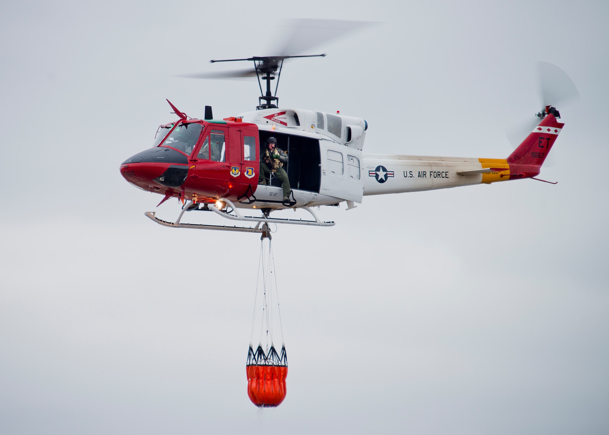 A 413th Flight Test Squadron UH-1 Huey carries a bucket of water through the air during a training mission at Eglin Air Force Base, Fla.  The water bucket operations training is required for flight crews to maintain their firefighting proficiencies.  The 413th helicopters can be tasked by the 96th Test Wing to support Jackson Guard with fire management.  They supported a firefighting effort during a range fire North of Hurlburt Field in May 2012. (U.S. Air Force photo/Samuel King Jr.)