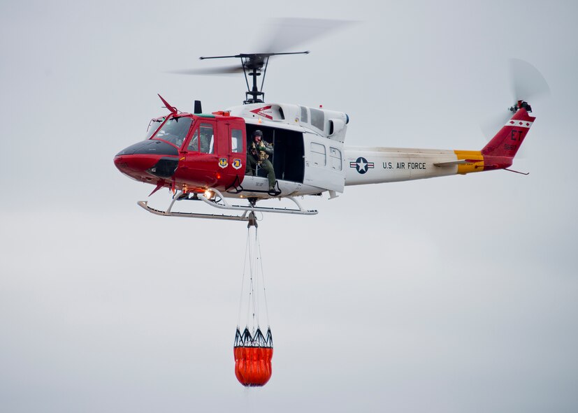 A 413th Flight Test Squadron UH-1 Huey carries a bucket of water through the air during a training mission at Eglin Air Force Base, Fla.  The water bucket operations training is required for flight crews to maintain their firefighting proficiencies.  The 413th helicopters can be tasked by the 96th Test Wing to support Jackson Guard with fire management.  They supported a firefighting effort during a range fire North of Hurlburt Field in May 2012. (U.S. Air Force photo/Samuel King Jr.)