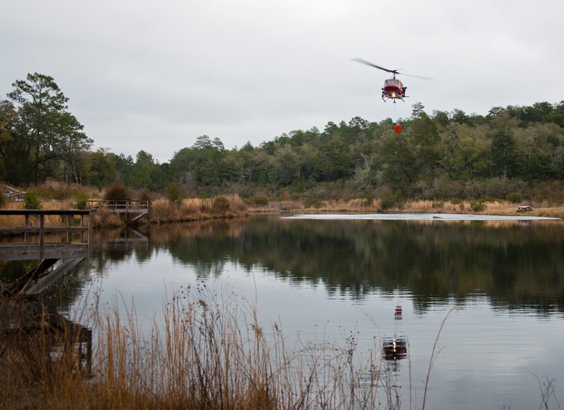 A 413th Flight Test Squadron UH-1 Huey crosses approaches Anderson Pond to pick up a bucket of water during a training mission at Eglin Air Force Base, Fla.  The water bucket operations training is required for flight crews to maintain their firefighting proficiencies.  The 413th helicopters can be tasked by the 96th Test Wing to support Jackson Guard with fire management.  They supported a firefighting effort during a range fire North of Hurlburt Field in May 2012.  (U.S. Air Force photo/Samuel King Jr.)