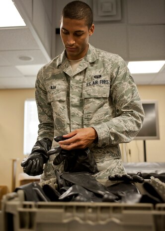 Senior Airman Bryant Ash, 99th Communication Squadron, puts on protective gloves during the chemical, biological, radiological and nuclear defense survival skills training course at Nellis Air Force Base, Nev., April 30, 2015. The training course is mandatory for Airmen who are deploying, going TDY, or making a permanent change of station to an area outside of the continental United States. (U.S. Air Force photo by Airman 1st Class Jake Carter)