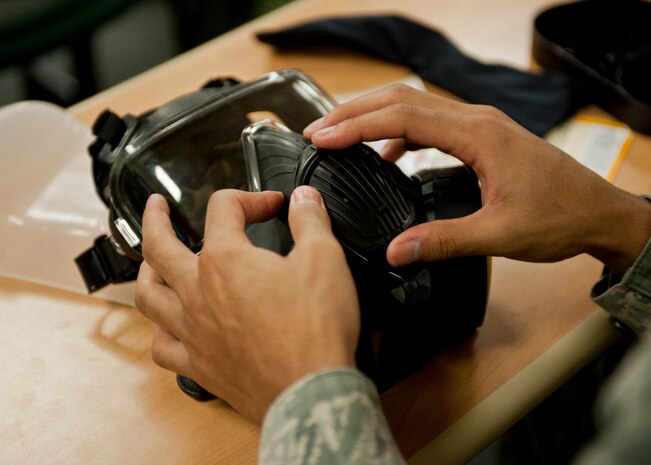Senior Airman Bryant Ash, 99th Communication Squadron, places his gas mask’s drinking tube in the stored position during a chemical, biological, radiological and nuclear defense survival skills training course at Nellis Air Force Base, Nev., April 30, 2015. CBRN training refreshes Airmen in the proper procedures to take if in contact with a contaminated substance. (U.S. Air Force photo by Airman 1st Class Jake Carter)