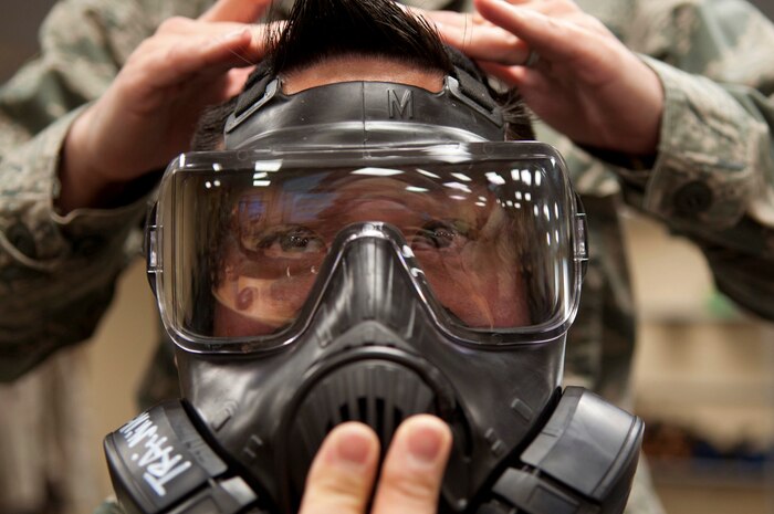 Tech. Sgt. Dave Rivera, 99th Medical Group¬, holds his gas mask in place on his face during a chemical, biological, radiological and nuclear defense survival skills training course on Nellis Air Force Base, Nev., April 30, 2015. The course consists of individual and team demonstration performance objectives that provide hands-on training and evaluation of knowledge acquired. (U.S. Air Force photo by Airman 1st Class Mikaley Towle)