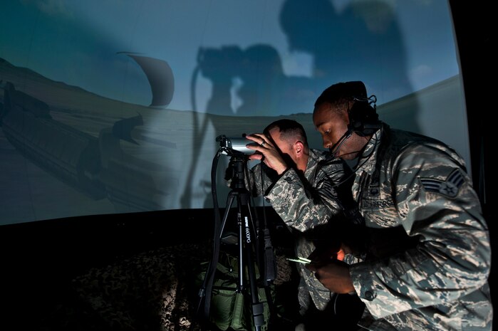 A tactical air control party Airman with the 14th Air Support Operations Squadron, Pope Field, N.C., gets feedback from a joint terminal attack controller instructor assigned to the 6th Combat Training Squadron during a close air support training scenario inside the 6th CTS’ JTAC virtual training facility at Nellis Air Force Base, Nev., April 29, 2015. JTACS are responsible for providing a link between ground forces and air assets above, as well as advising ground commanders on how best to employ joint airpower capabilities. (U.S. Air Force photo by Senior Airman Joshua Kleinholz)