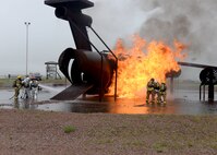 ALTUS AIR FORCE BASE, Okla. – Members from the 97th Air Mobility Wing fight a training aircraft fire during a fire exercise at the burn pit, May 8, 2015. The exercise held by the fire department allowed wing leaders to participate in simulated cargo, passenger and flight deck fires to gain an insight on how to successfully contain and put out a fire. (U.S. Air Force photo by Senior Airman Franklin R. Ramos/Released)