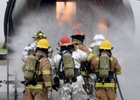 ALTUS AIR FORCE BASE, Okla. – Members from the 97th Air Mobility Wing enter a training aircraft during a fire exercise at the burn pit, May 8, 2015. The wing’s fire department and leadership simulated cargo, passenger and flight deck fires to be extinguished. (U.S. Air Force photo by Senior Airman Franklin R. Ramos/Released)