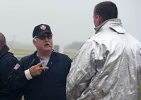 ALTUS AIR FORCE BASE, Okla. – Nils Brobjorg, 97th Civil Engineer Squadron fire department assistant chief of training, briefs U.S. Air Force Col. Bill Spangenthal, 97th Air Mobility Wing commander, about emergency signals during a fire exercise at the burn pit, May 8, 2015. The fire department allowed wing leaders to put out a training aircraft fire in order to have a better understanding of the procedures followed to successfully extinguish the flames. (U.S. Air Force photo by Senior Airman Franklin R. Ramos/Released)