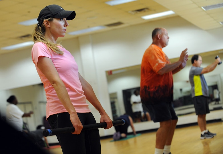 Woman in pink shirt and black hat exercising