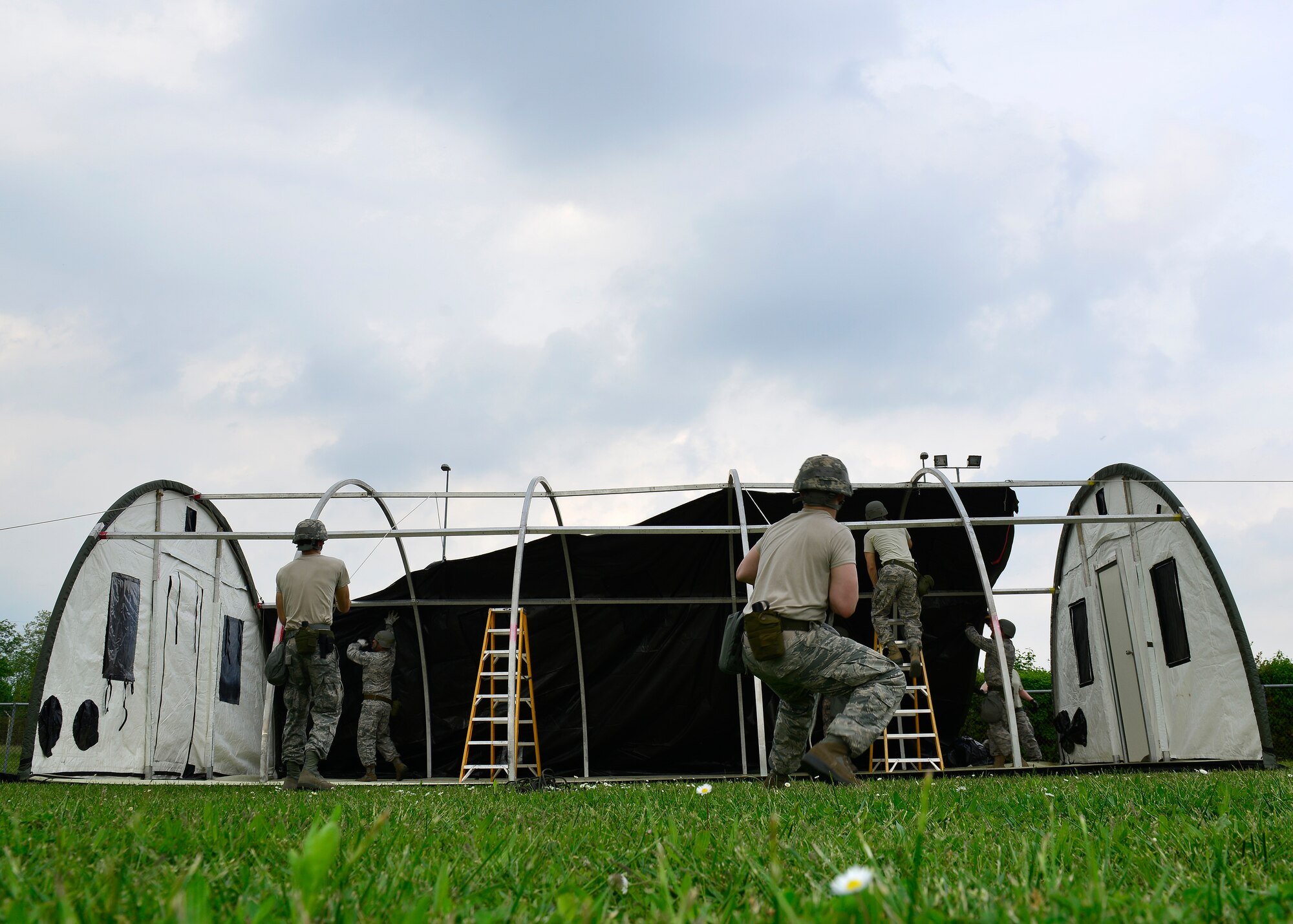 U.S. Air Force 31st Civil Engineer Squadron members pull the remaining sides of the tent into place during inspection Maroon Excavator, May 6, 2015 at Area D Aviano Air Base, Italy.  The 31st CES constructs tents to simulate setting up a base in a deployed location.  (U.S. Air Force photo by Airman 1st Class Cary Smith/Released)