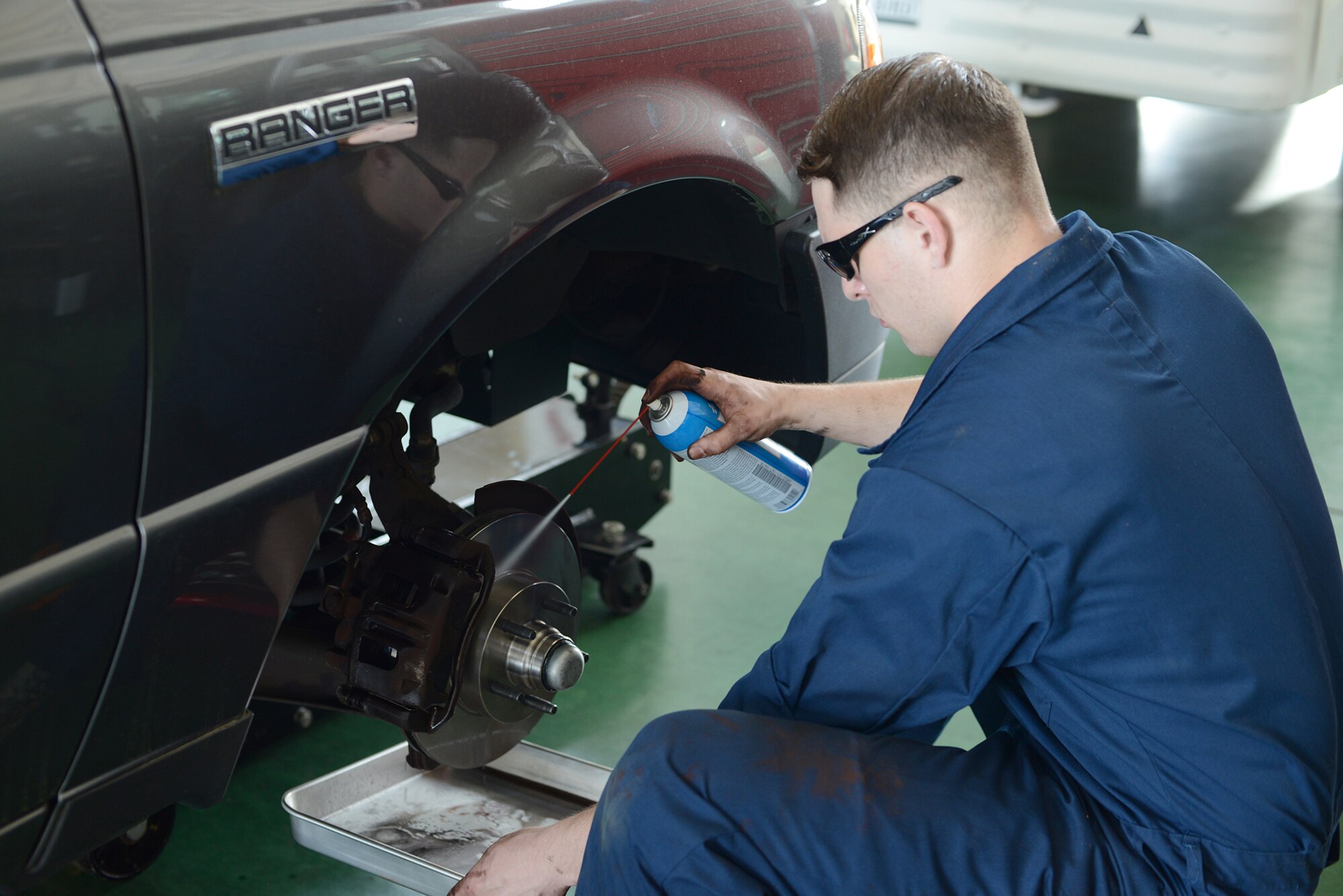 Senior Airman Brandon Higginbotham, 374th Logistics Readiness Squadron vehicle maintenance journeyman, sprays break cleaner to remove manufacturing oils from a new rotor at Yokota Air Base, Japan, April 28, 2015. Removing the oils prevents damage to the pads and rotor. (U.S. Air Force photo by Airman 1st Class David C. Danford/Released)