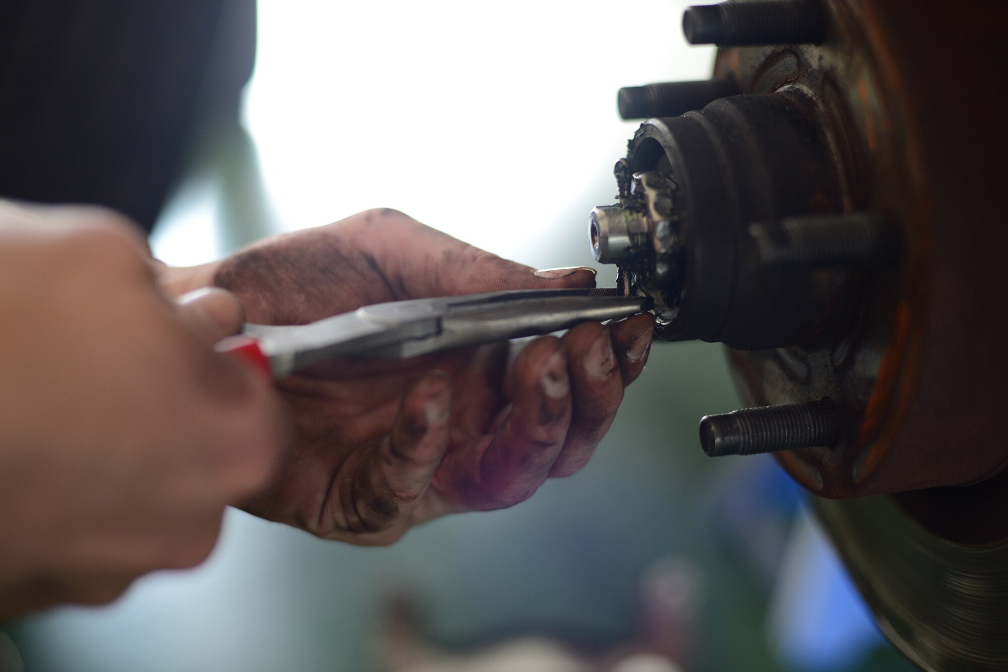 Senior Airman Brandon Higginbotham, 374th Logistics Readiness Squadron vehicle maintenance journeyman, removes a cotter pin from the rotor hub assembly while conducting scheduled vehicle maintenance at Yokota Air Base, Japan, April 28, 2015. Cotter pin tines are bent around the bolt to provide a secure connection within the assembly. (U.S. Air Force photo by Airman 1st Class David C. Danford/Released)