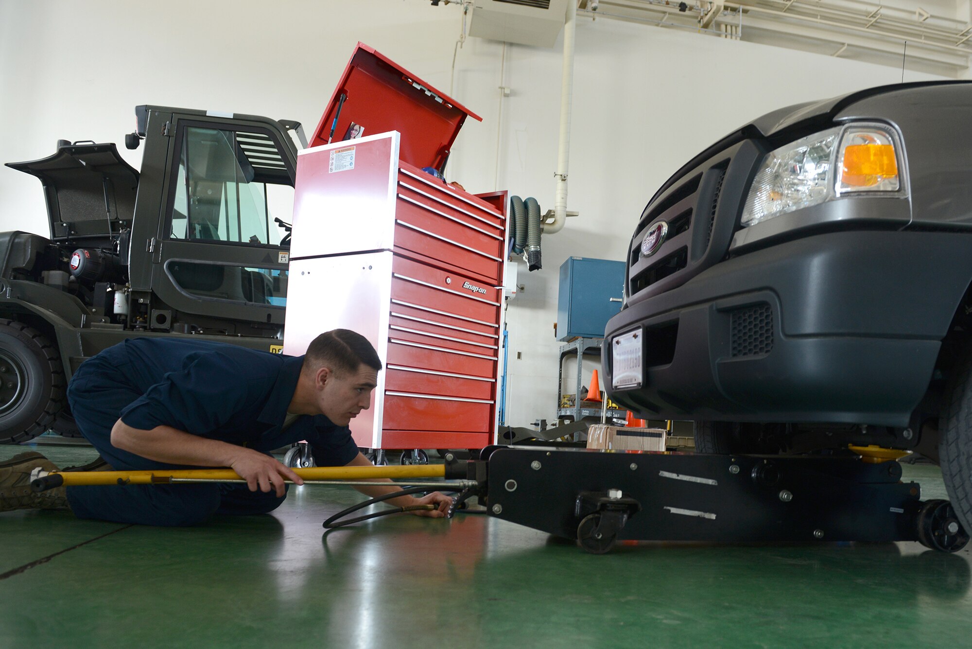Senior Airman Brandon Higginbotham, 374th Logistics Readiness Squadron vehicle maintenance journeyman, positions a jack under a government vehicle at Yokota Air Base, Japan, April 28, 2015. The truck was brought into the vehicle maintenance shop to assess the front brakes. (U.S. Air Force photo by Airman 1st Class David C. Danford/Released)