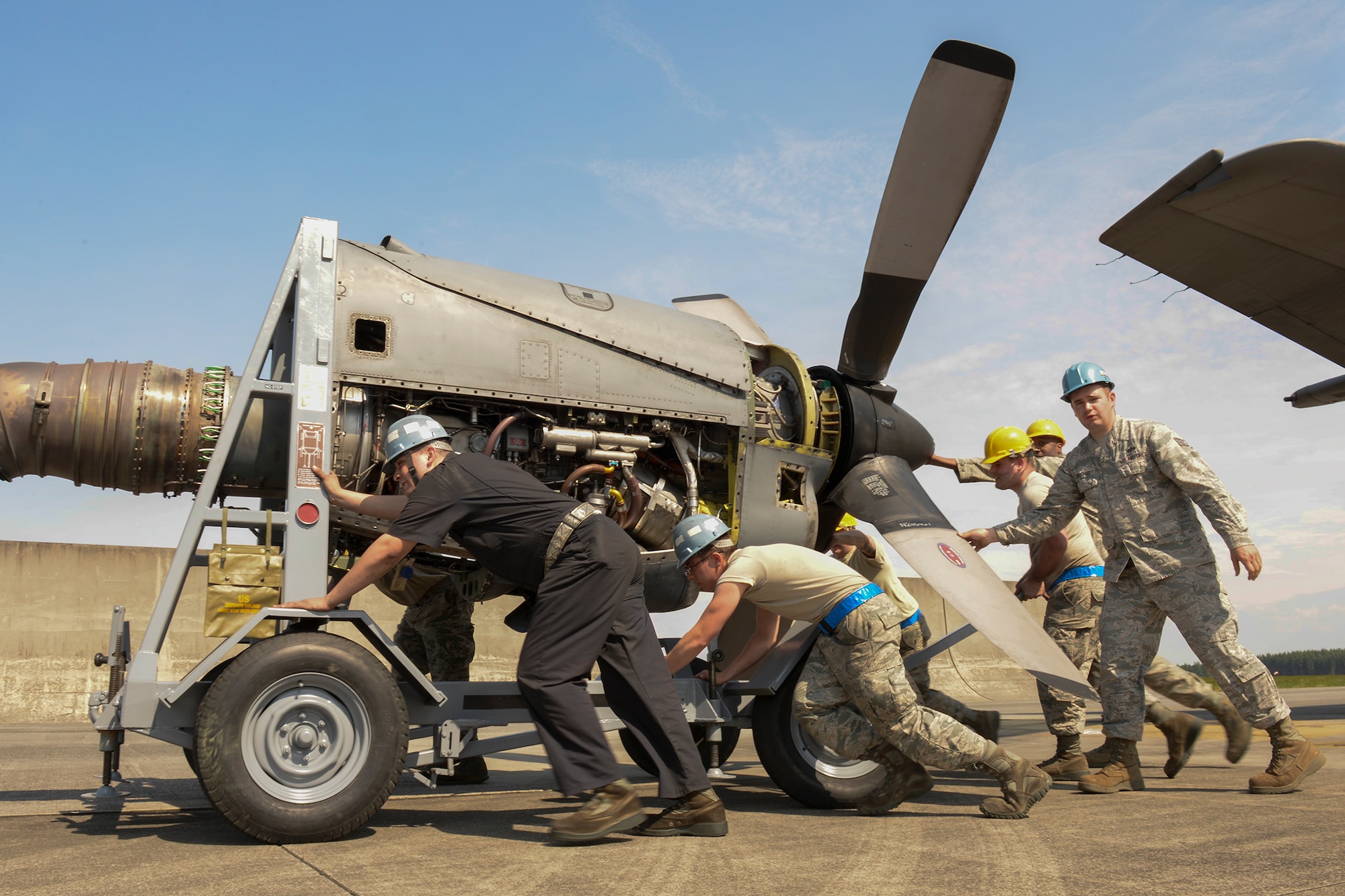 Members with the 374th Maintenance Squadron and the 374th Aircraft Maintenance Squadron work as a team to transport the engine of a C-130 Hercules, April 29, 2015 at Yokota Air Base, Japan. All four engines had to be removed for repair after a routine annual inspection. (U.S. Air Force photo by Airman 1st Class Elizabeth Baker/Released)