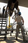 Staff Sgt. Dwayne Trett, aerospace propulsion craftsman with the 374th Maintenance Squadron, holds a strap to steady the engine of a C-130 Hercules, April 29, 2015 at Yokota Air Base, Japan. The process of removing the engine for repair took about 45 minutes of care and precision. (U.S. Air Force photo by Airman 1st Class Elizabeth Baker/Released)