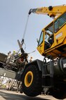 Crewmembers of the 374th Maintenance Squadron and the 374th Air Maintenance Squadron coordinate with a crane operator with the 374th Civil Engineer Squadron to secure the crane to a C-130 Hercules engine, April 29, 2015 at Yokota Air Base, Japan. After maintainers harnessed the engine, the crane operator lifted the engine off its wing and lowered it to the ground. (U.S. Air Force photo by Airman 1st Class Elizabeth Baker/Released)