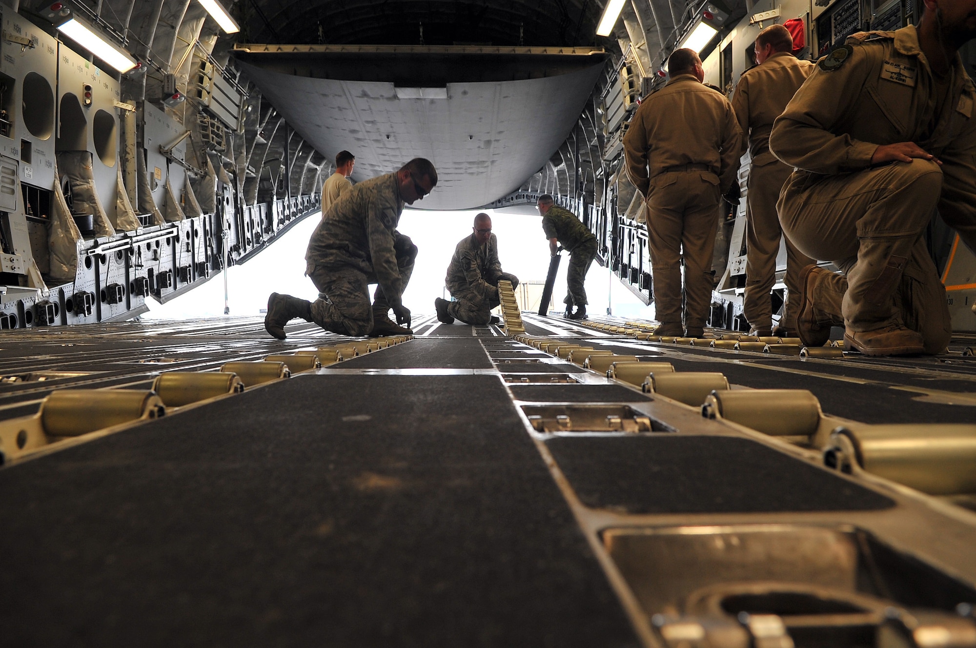 U.S. Air Force Staff Sgt. Josh Foley, 36th Mobility Response Squadron aerial port supervisor, guides a Canadian Forces member unloading equipment from their C-17 Globemaster III May 9, 2015, at the Tribhuvan International Airport in Kathmandu, Nepal. The Nepalese Army and Airmen worked together to process 537,816 pounds of cargo in a 24-hour period from 13 aircraft delivering relief supplies after a 7.8 magnitude earthquake struck the nation April 25, 2015. (U.S. Air Force photo by Staff Sgt. Melissa B. White/Released)