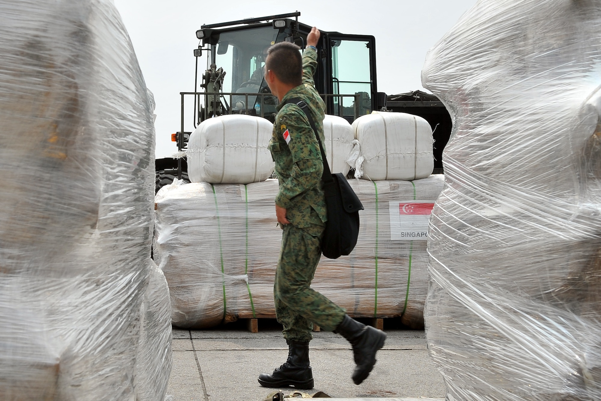 A Republic of Singapore Air Force member guides a U.S. Air Force 36th Contingency Response Group Airman unloading cargo from an RSAF C-130 Hercules May 9, 2015, at the Tribhuvan International Airport in Kathmandu, Nepal. The Nepalese army and Airmen worked together to process 537,816 pounds of cargo in a 24-hour period from 13 aircraft delivering relief supplies after a magnitude 7.8 earthquake struck the nation April 25, 2015. (U.S. Air Force photo by Staff Sgt. Melissa B. White/Released)