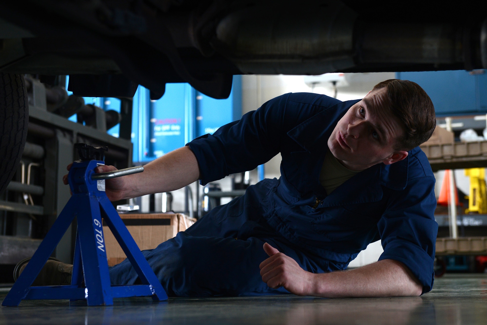 Senior Airman Brandon Higginbotham, a 374th Logistics Readiness Squadron vehicle maintenance journeyman, places jack stands under a government vehicle at Yokota Air Base, Japan, April 28, 2015. Stands are placed to ensure the safety of the mechanics working on vehicles. (U.S. Air Force photo/Airman 1st Class David C. Danford)