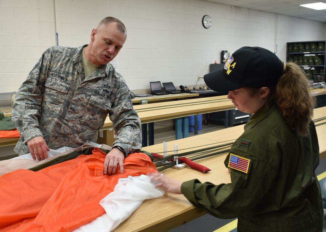 Master Sgt. Don McCormick, an aircrew life equipment craftsman with the 910th Airlift Wing, shows 12-year-old Celina Dennis of Poland, Ohio, how he inspects parachutes for defects here, May 6, 2015. Dennis was selected as the 910th Airlift Wing’s 61st Pilot for a Day, being sworn in as an honorary 2nd Lt. and treated to a day of military-themed activities here. Pilots for a Day are local children with chronic or life-threatening illnesses selected by Akron Children’s Hospital Boardman campus. (U.S. Air Force photo/Eric M. White)