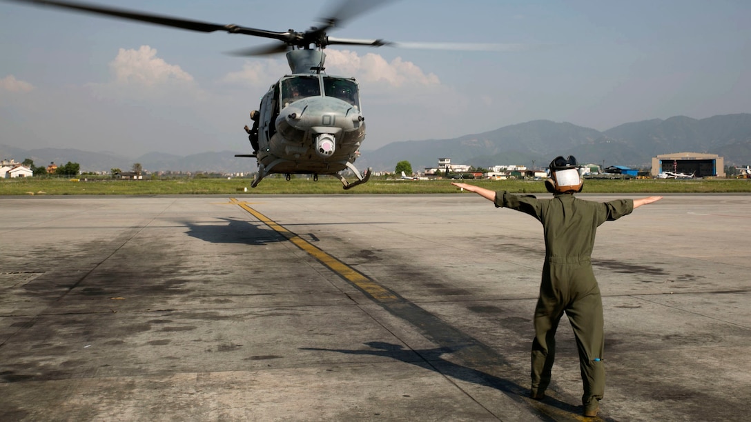 Cpl. Mackenzie Higgins guides a UH-1Y Huey for takeoff at the Tribhuvan International Airport in Kathmandu, Nepal, May 5. Marines with Marine Light Attack Helicopter Squadron 469 and Marine Medium Tilt Rotor Squadron 262 carried supplies in a UH-1Y Huey and MV-22 Ospreys to Charikot, Nepal. The supplies will provide Nepalese people with shelter after a 7.8 magnitude earthquake struck central Nepal, April 25, causing fatalities, injuries and significant damage. The government of Nepal declared a state of emergency and requested international assistance. The U.S. military, at the direction of the U.S. Agency for International Development, will continue to support Nepal as needed. HMLA-469 and VMM-262 are attached to Marine Aircraft Group 36, 1st Marine Aircraft Wing, III Marine Expeditionary Force. Higgins is a UH-1Y crew chief with HMLA-469 from Pala Way, California.
