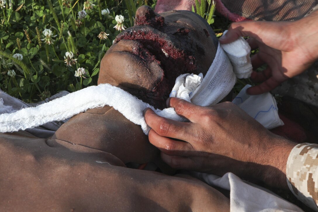 Pfc. Kevin J. Oronaponce, a rifleman with 2nd Battalion, 2nd Marine Regiment, 2nd Marine Division, wraps a facial wound on a mannequin during the final test for the Combat Trauma Care Course aboard Camp Lejeune, N.C., April 24, 2015. The additional stress from interactive mannequins and working under a time limit for the evacuation provided a more realistic environment to better prepare the Marines in case they would be called upon to use these techniques in real life. (U.S. Marine Corps photo by Pfc. David N. Hersey)