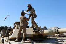Corporal Christian Bills, gunner, Company A, 1st Tank Battalion, 1st Marine Division, nicknamed “America’s Company,” hands a main gun round to Cpl. Jeffrey Buttler, tank mechanic, Co. A, during Exercise Desert Scimitar aboard Marine Corps Air Ground Combat Center Twentynine Palms, Calif., April 10, 2015. The training gave the Marines the opportunity to refine and rehearse essential combat skills needed in a battlefield environment. Desert Scimitar is an annual exercise that includes elements from the I Marine Expeditionary Force. The exercise focused on conventional operations and provided realistic training that prepared Marines for overseas operations. (U.S. Marine Corps photo by Sgt. Christopher J. Moore/Released)