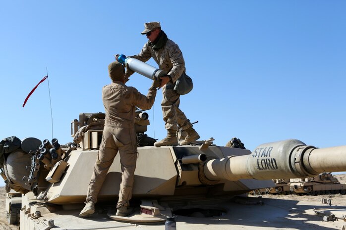 Corporal Christian Bills, gunner, Company A, 1st Tank Battalion, 1st Marine Division, nicknamed “America’s Company,” hands a main gun round to Cpl. Jeffrey Buttler, tank mechanic, Co. A, during Exercise Desert Scimitar aboard Marine Corps Air Ground Combat Center Twentynine Palms, Calif., April 10, 2015. The training gave the Marines the opportunity to refine and rehearse essential combat skills needed in a battlefield environment. Desert Scimitar is an annual exercise that includes elements from the I Marine Expeditionary Force. The exercise focused on conventional operations and provided realistic training that prepared Marines for overseas operations. (U.S. Marine Corps photo by Sgt. Christopher J. Moore/Released)