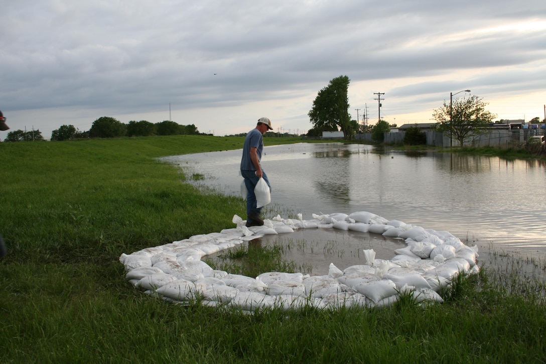 A representative from the Lower Papio South Natural Resources District places a sandbag on a ring of sandbags around a boil discovered along Salt Creek in Lincoln, Nebraska, across the creek from the Waste Water Treatment Plant