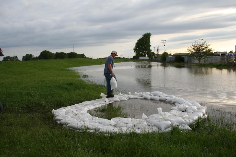 A representative from the Lower Papio South Natural Resources District places a sandbag on a ring of sandbags around a boil discovered along Salt Creek in Lincoln, Nebraska, across the creek from the Waste Water Treatment Plant