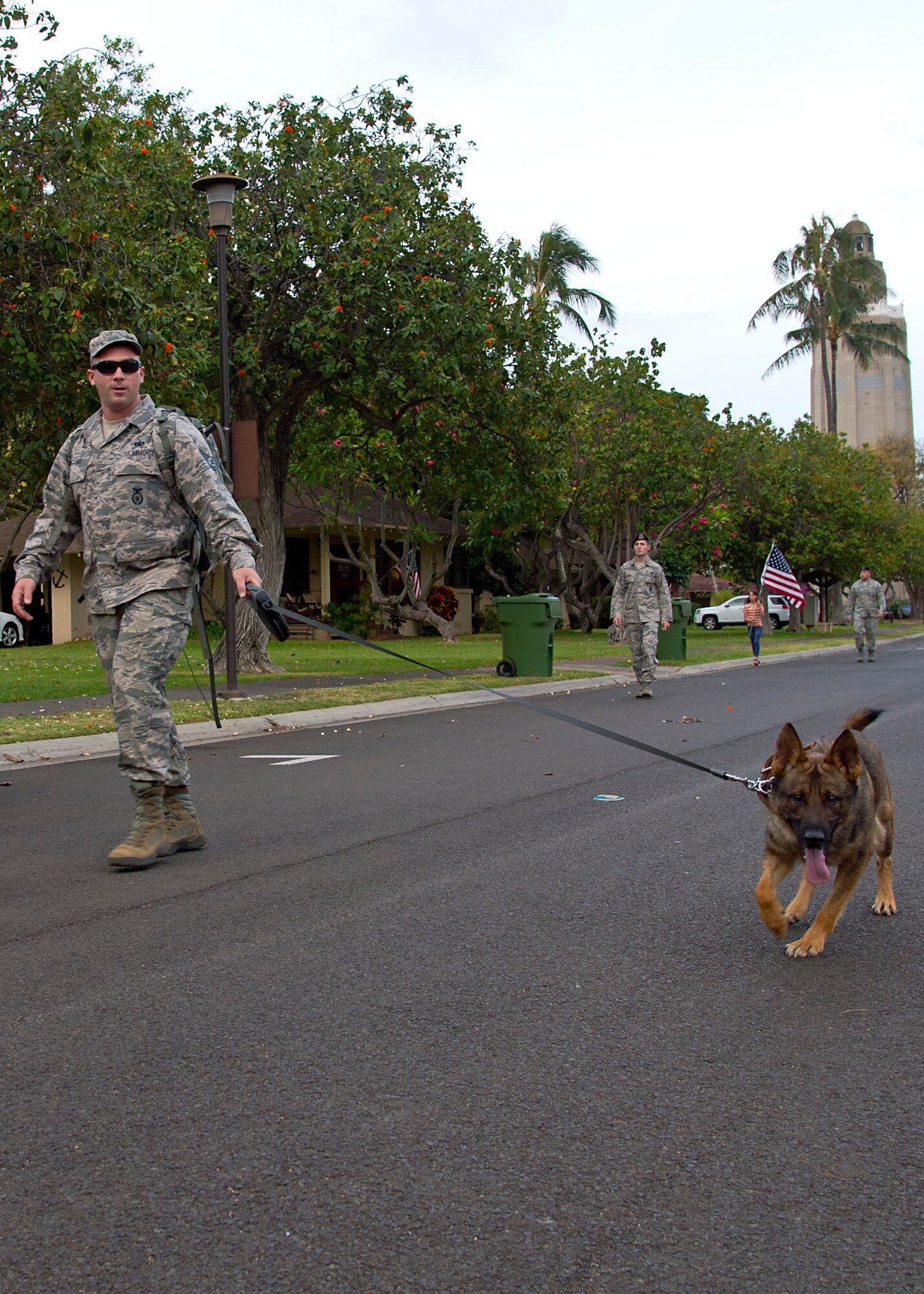 Tech Sgt. Jonathan Williams, from the647th Security Forces Squadron, walks down Porter Avenue with his military working dog Jon during a police week ruck march on Joint Base Perl Harbor-Hickam, Hawaii, May 5, 2015. Each May, during National Police Week, the U.S. recognizes the service law enforcement and remembers those who have lost their lives in the line of duty. (U.S. Air Force Photo by Tech Sgt. Aaron Oelrich/Released) 