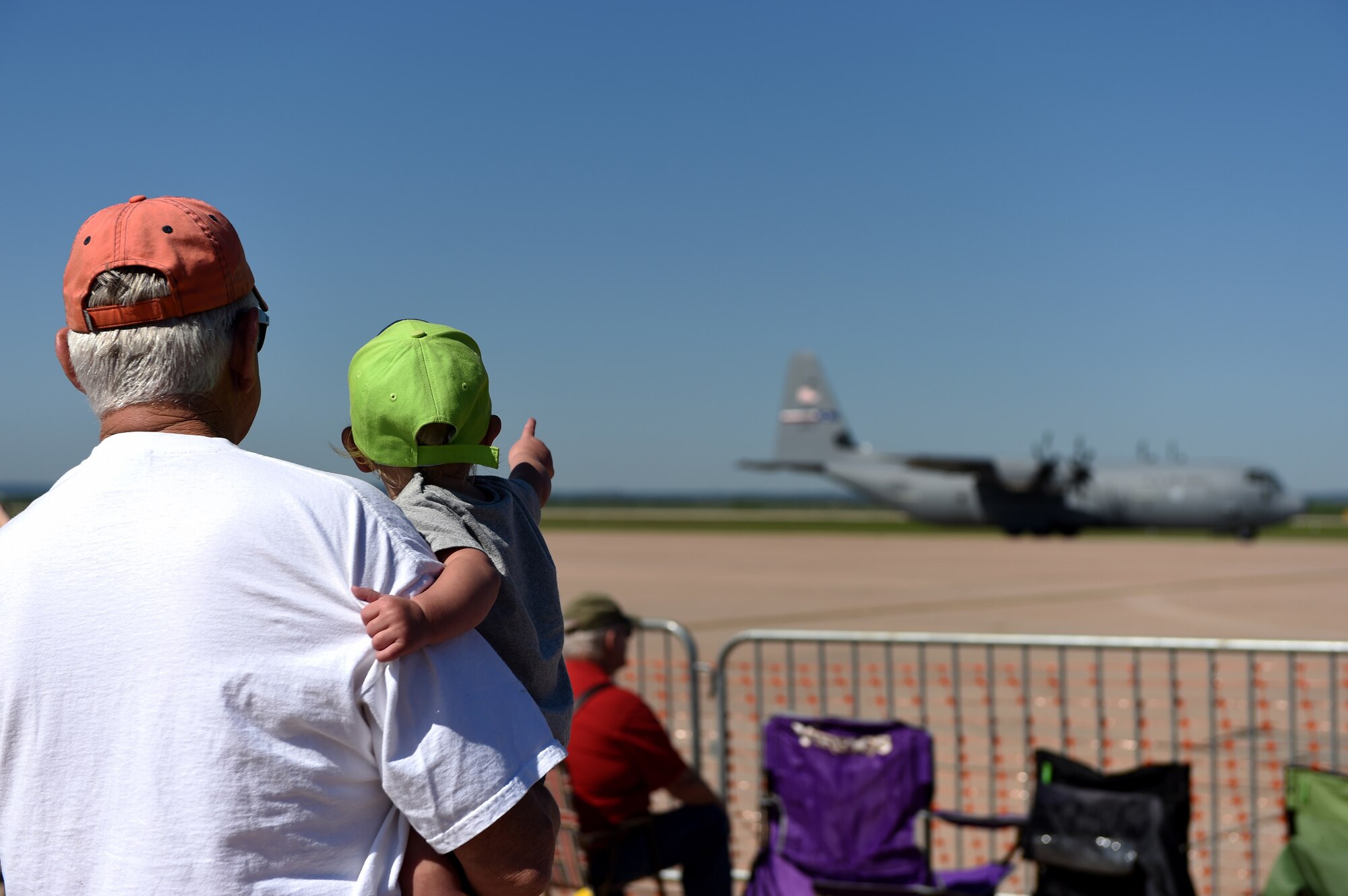 A grandfather and grandchild watch as a C-130J Super Hercules taxis down the runway for takeoff May 2, 2015, at Dyess Air Force Base, Texas. C-130Js performed a simulated supply airdrop during the Dyess Big Country Airfest. Over 26,000 spectators came to watch performances during the two days the airshow took place. (U.S. Air Force photo by Airman 1st Class Alexander Guerrero/Released)
