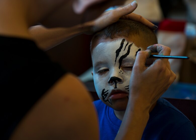 Meghan Hansen paints Ezekiel Adame’s face like a tiger at the face-painting booth during the 6th Ranger Training Battalion’s Open House event May 9 at Eglin Air Force Base, Fla. The event was a chance for the public to learn how Rangers train and operate. The event displays showed equipment, weapons, a reptile zoo, face painting and weapon firing among others. The demonstrations showed off hand-to-hand combat, a parachute jump, snake show, and Rangers in action. (U.S. Air Force photo/Tech. Sgt. Jasmin Taylor)