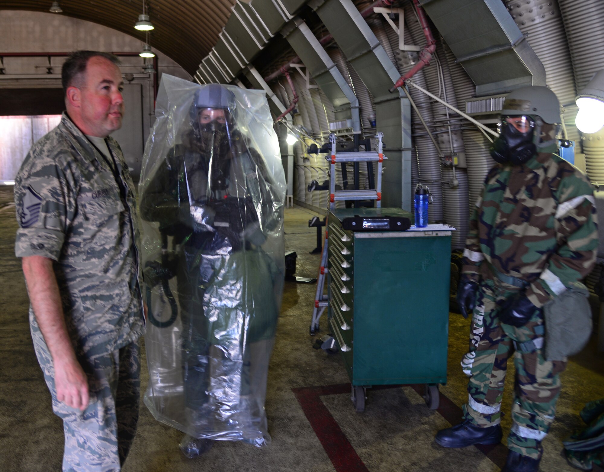 Master Sgt. Gregory Currey, 51st Operations Support Squadron chief of aircrew flight equipment, 1st Lt. Matthew Barrett, 25th Fighter Squadron pilot, and Tech. Sgt. James Menden, 51st Maintenance Group aircraft maintenance instructor, pause before filming a training video May 4, 2015, at Osan Air Base, Republic of Korea. The Airmen are preparing for the Beverly Midnight 15-02 which is designed to test American forces in the ROK on their mission readiness in the event of an emergency or wartime environment. (U.S. Air Force photo by Staff Sgt. Benjamin Sutton/Released) 