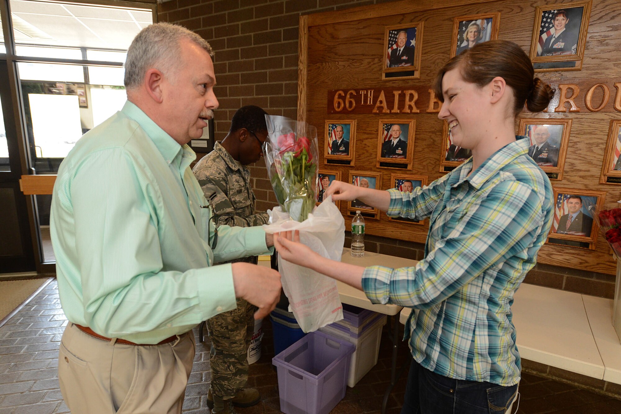 Airman 1st Class Kara Watts, 66th Air Base Group administration specialist, hands Ed Gilbertson a dozen red roses as part of a Mother’s Day fundraiser hosted by the Patriot Enlisted Association, May 8. The PEA sold 150 dozen roses during this event. (U.S. Air Force photo by Jerry Saslav)