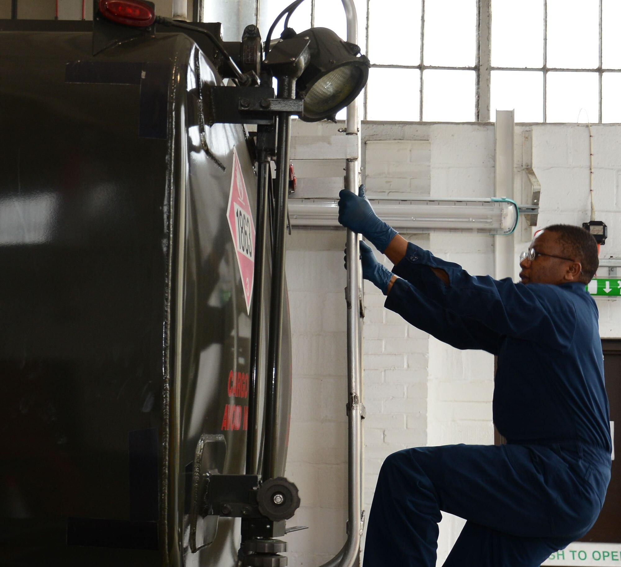 U.S. Air Force Staff Sgt. Peter Mwangi, 100th Logistics Readiness Squadron NCO in charge of refueling maintenance from Las Vegas, Nev., climbs to the top of a fuel truck to perform maintenance April 23, 2015, on RAF Mildenhall, England. Mwangi climbed the truck to work on the refueling hose. (U.S. Air Force photo by Gina Randall/Released) 