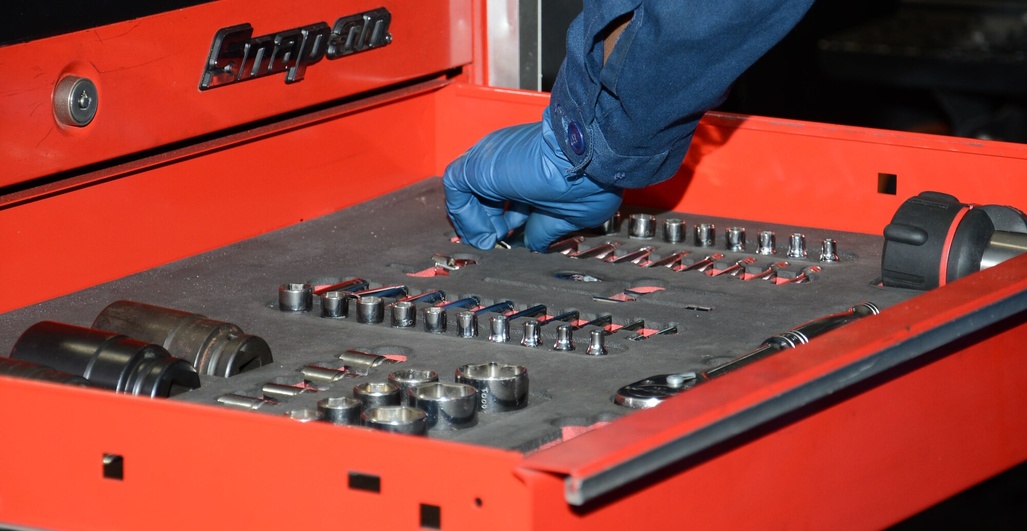 U.S. Air Force Staff Sgt. Peter Mwangi, 100th Logistics Readiness Squadron NCO in charge of refueling maintenance from Las Vegas, Nev., selects a tool during maintenance work on an R-11 fuels truck refueling hose April 23, 2015, on RAF Mildenhall, England. Mwangi prepared to remove  the 100-foot-long, two-and-a-half inch underwing refueling hose which requires team work and precision to ensure efficiency and mission success. (U.S. Air Force photo by Gina Randall/Released)