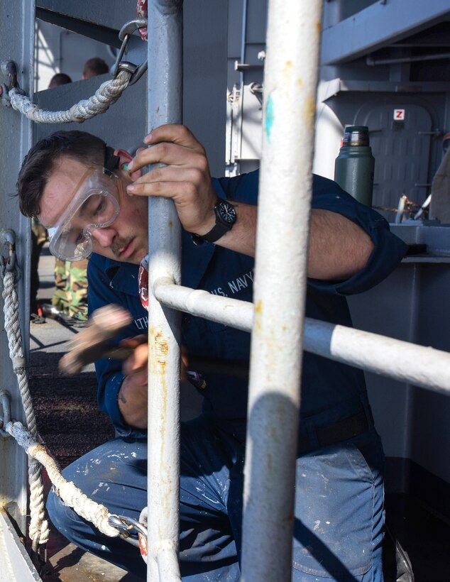 U.S. Navy Seaman Jake Walthall chips paint off a guard rail on the fantail of USS John C. Stennis in the Pacific Ocean, May 1, 2015.
