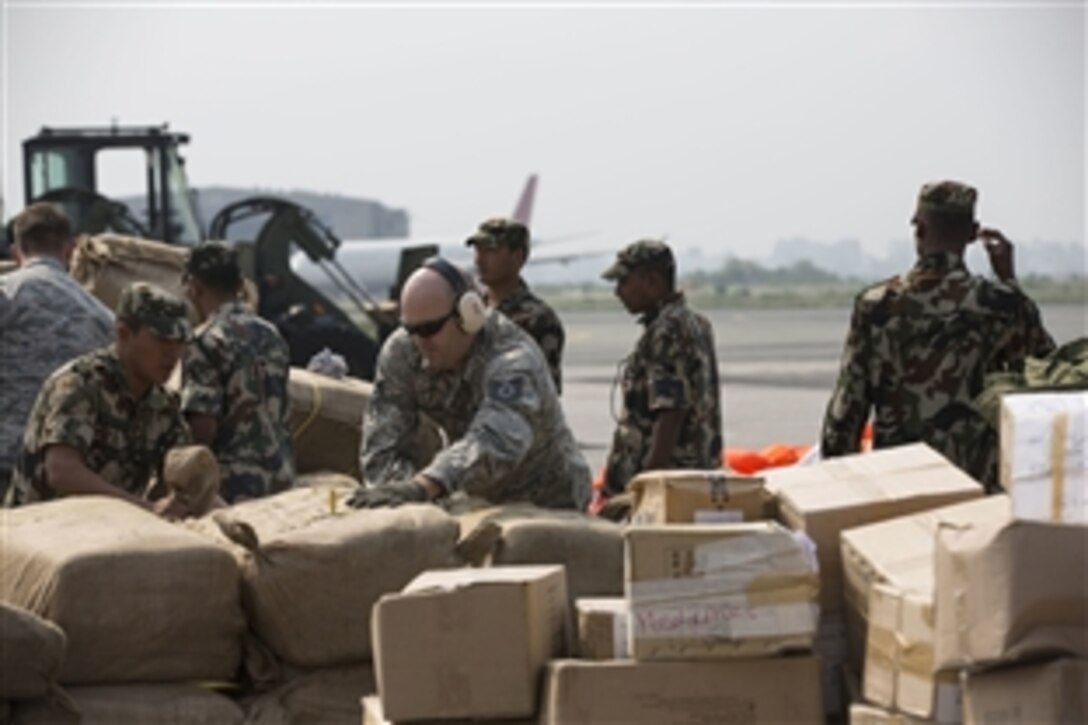 U.S. Airmen and Nepalese service members open a pallet of humanitarian aid as part of the Joint Task Force 505 humanitarian assistance and earthquake relief effort in Nepal, May 7, 2015.